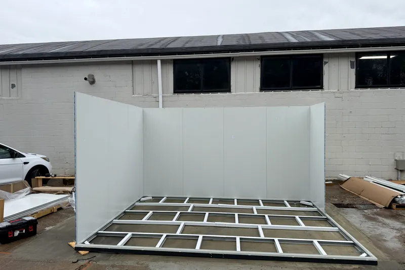 Steel floor frame of a prefab office with the first insulated wall panels standing
